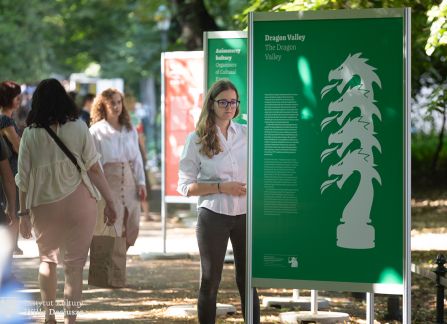 fotografia. wystawa Wyszehrad to ludzie na krakowskich plantach. ludzie przechadzają się pomiędzy plakatami ustawionymi w rzędzie wzdłuż alejki.